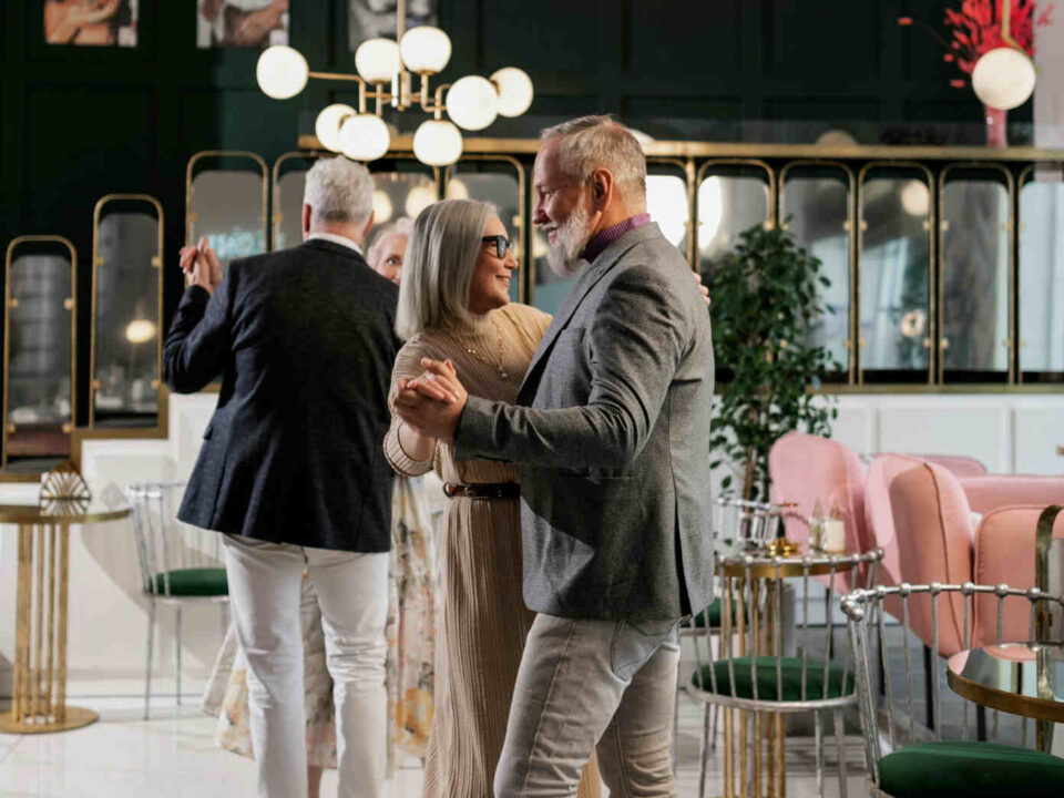 an old couple at an event slow dance, sway and serenade