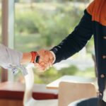 how to get your first paid dj gigs with two people shaking hands, representing social interactions for referrals