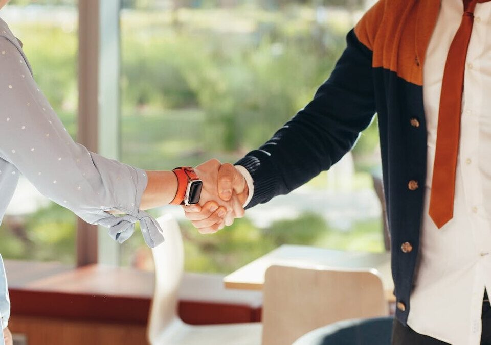 how to get your first paid dj gigs with two people shaking hands, representing social interactions for referrals