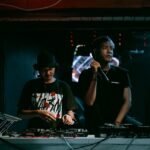 person with mic standing next to a dj to illustrate how to deal withl difficult situations at a bar