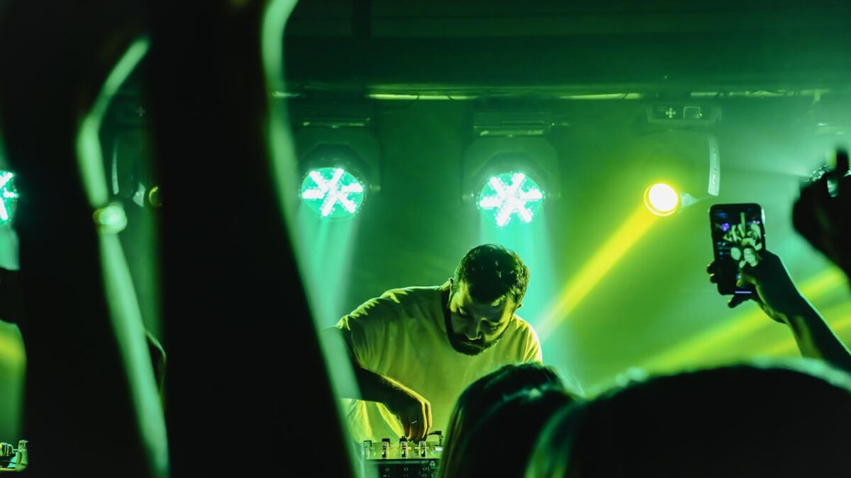 busy man behind decks in front of large crowd to highlight how DJs prepare for busy schedules