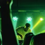busy man behind decks in front of large crowd to highlight how DJs prepare for busy schedules