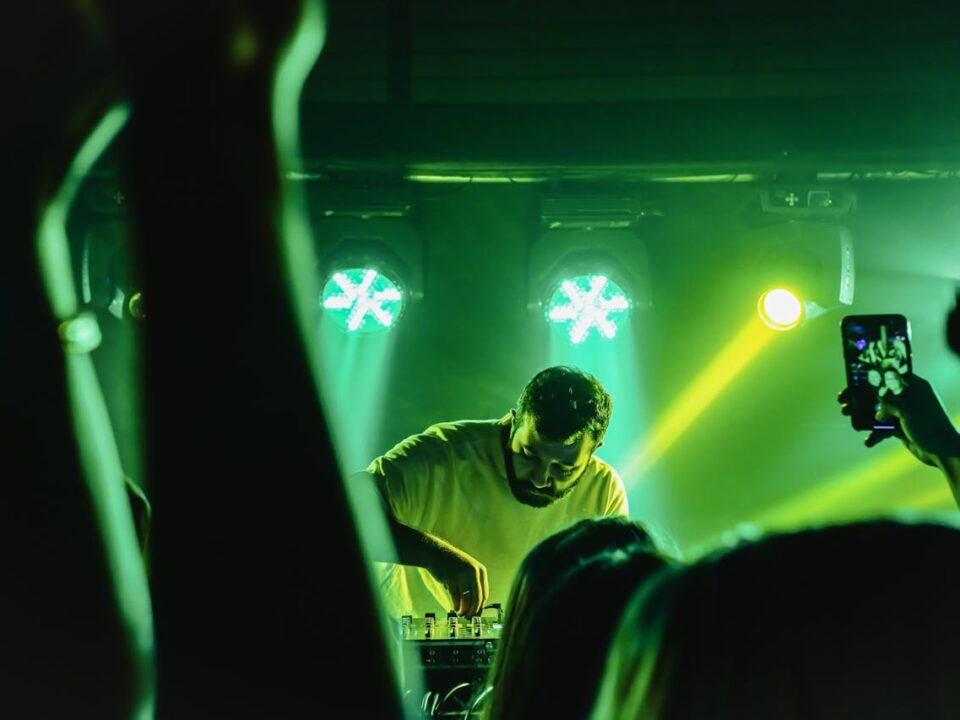 busy man behind decks in front of large crowd to highlight how DJs prepare for busy schedules